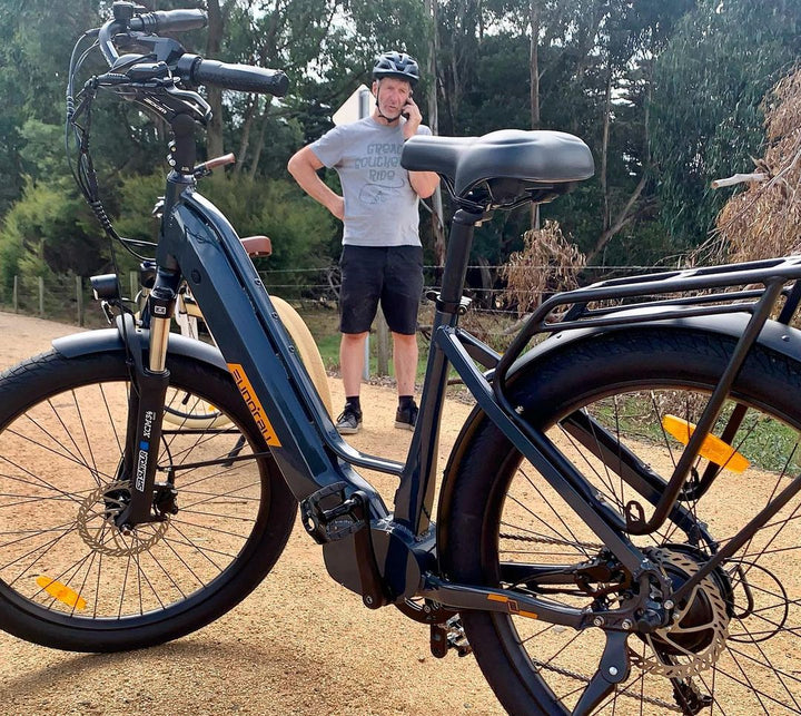 A rider taking a phone break Eunorau Meta275-ST 500W Electric Cruiser Bike with Torque Sensor for Commuters on a bike path